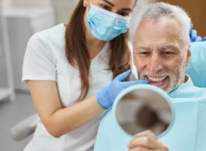 Man Looking At Dental Implants in Mirror