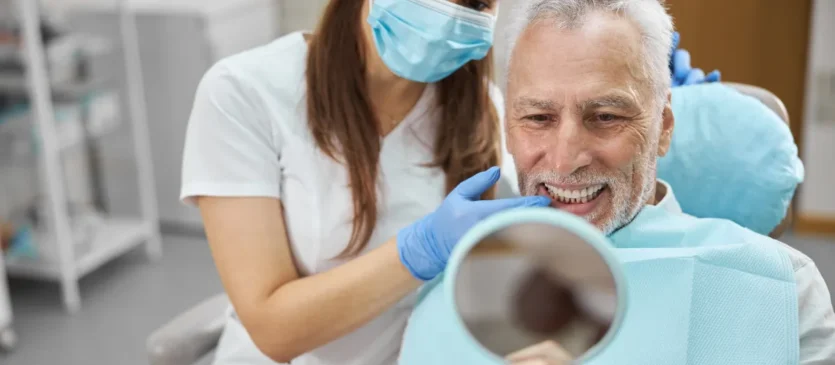 Man Looking At Dental Implants in Mirror